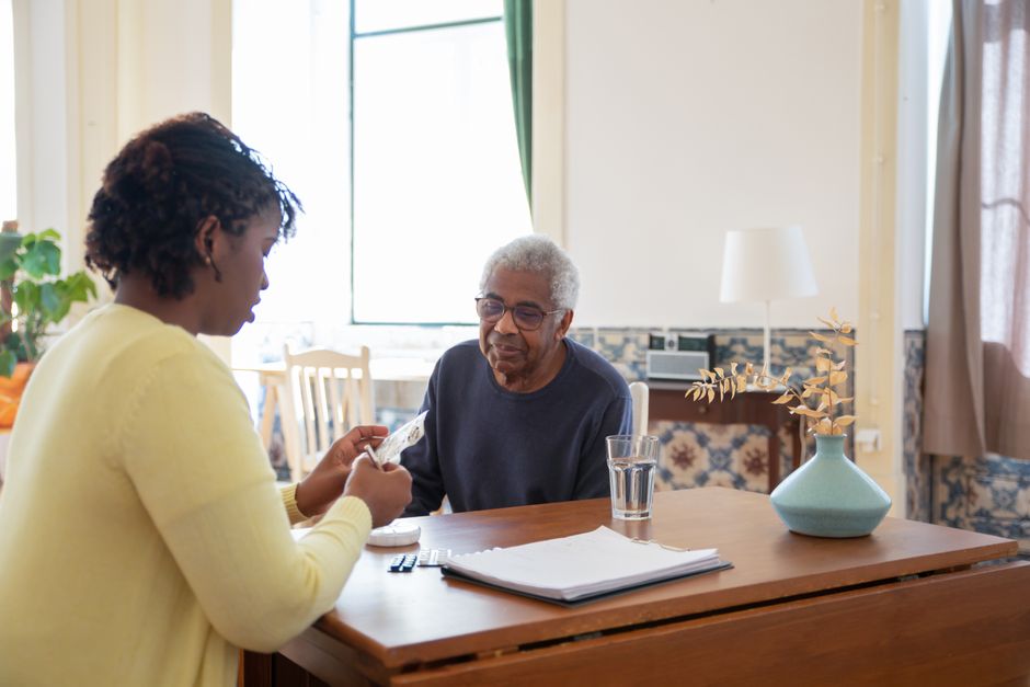 Caregiver assisting elderly man with medication