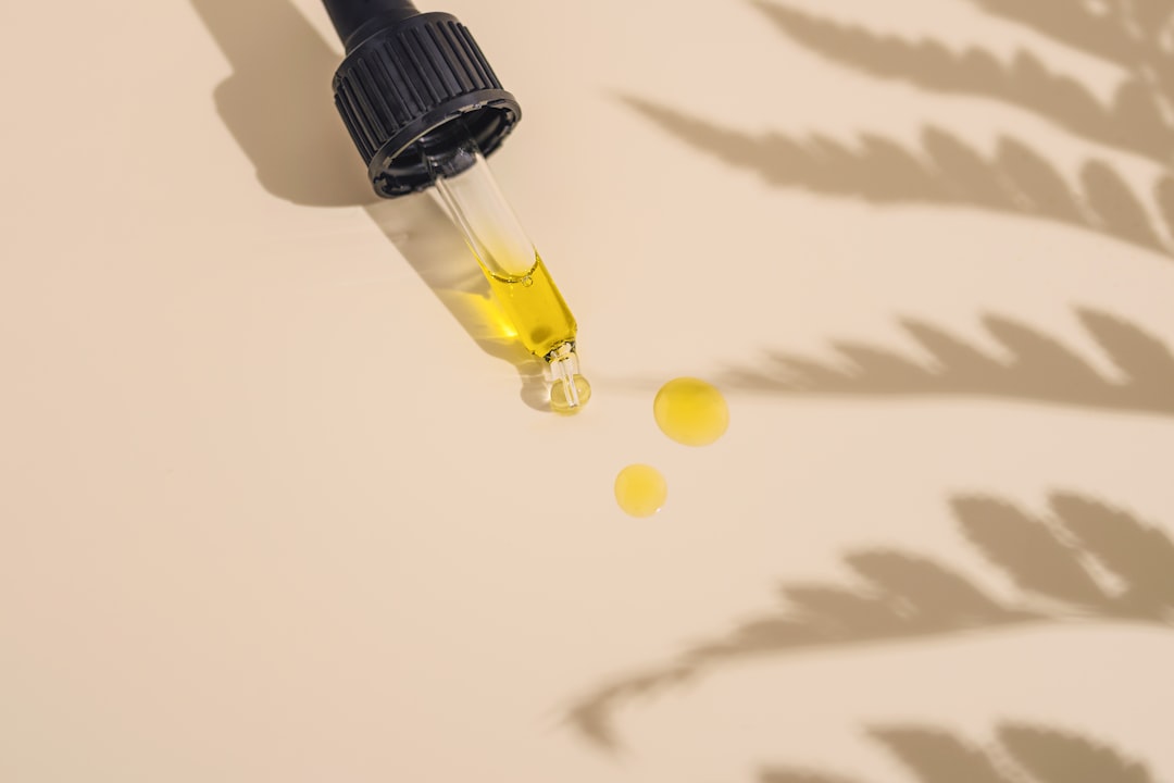 Dropper and yellow oil drops casting shadows