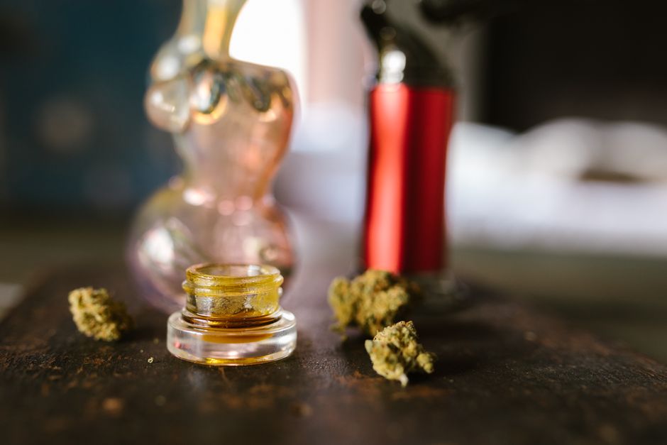 Cannabis extract, buds, and glass rig on table