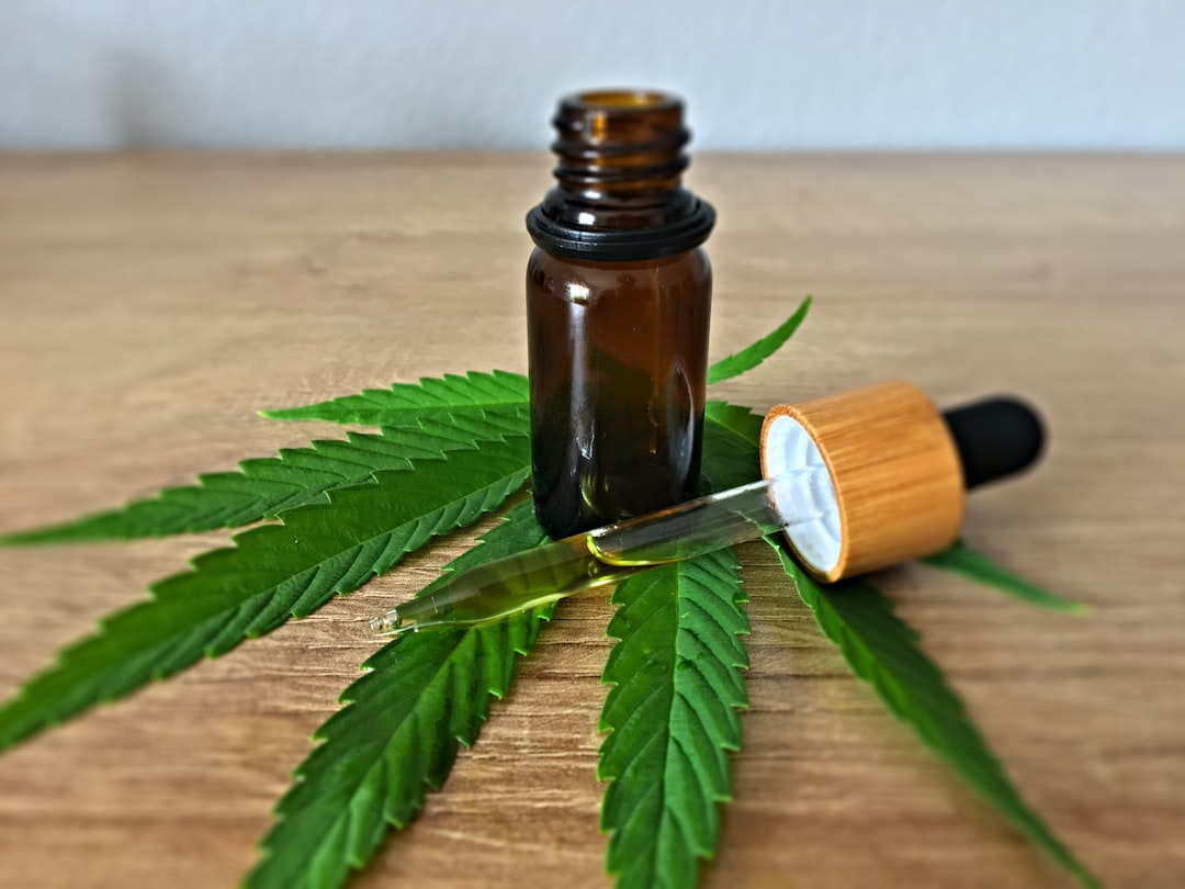Dropper bottle on cannabis leaves on wood