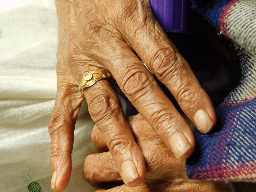 Elderly hands with gold ring and blanket