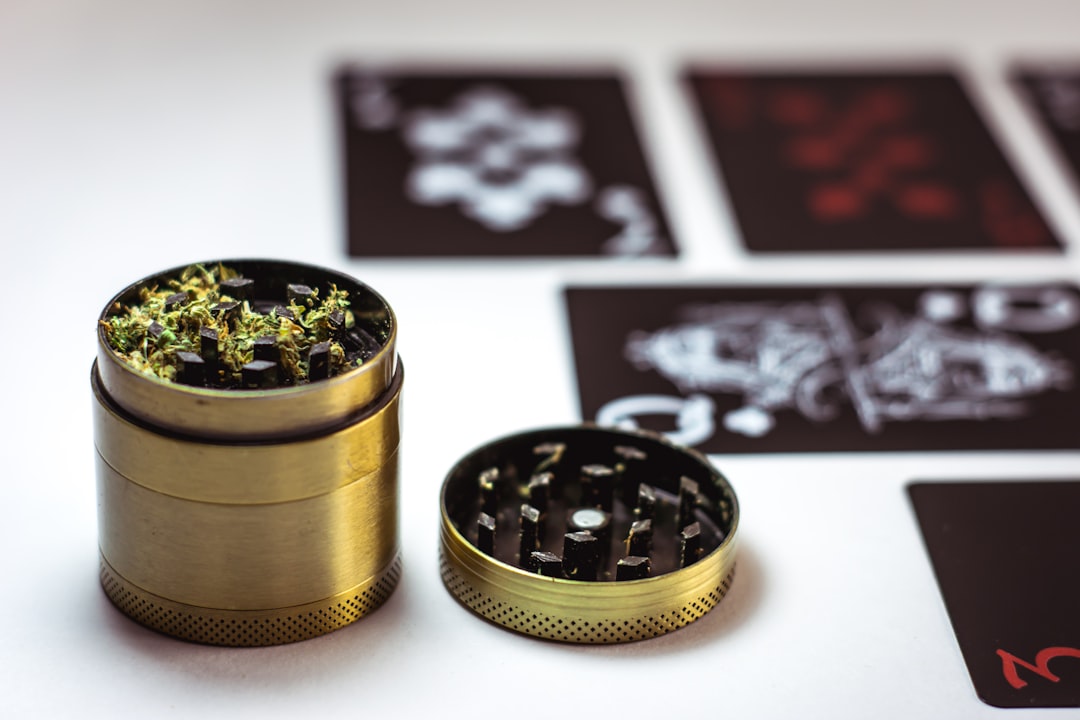 Open herb grinder near playing cards