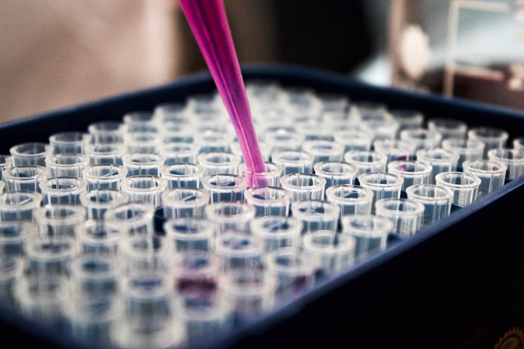 Pink pipette dispensing liquid into test tubes